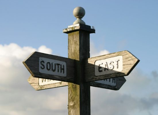 Directional signpost with multiple arrows pointing different ways, representing the challenge mid-market companies face in choosing the right AI strategy